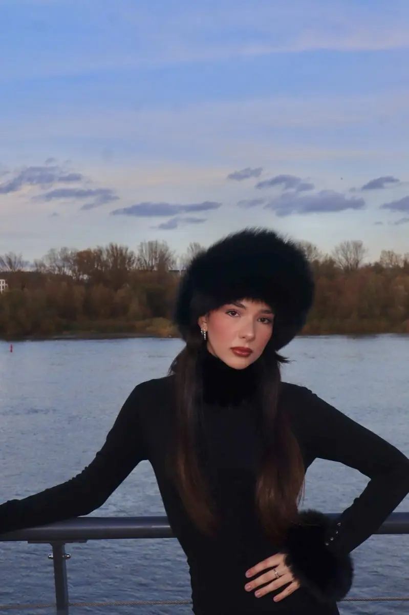 Black real fur hat worn by the river at dusk